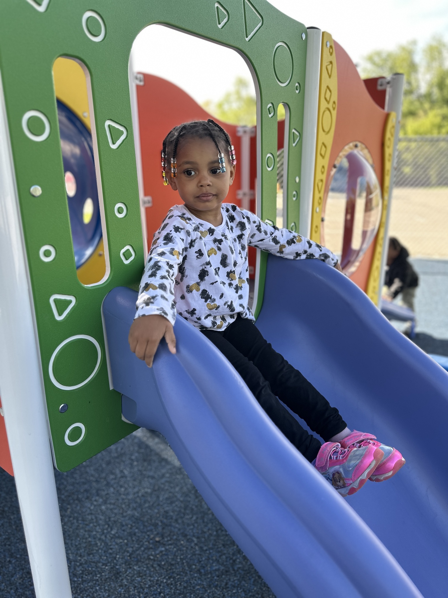 A young child sits at the top of a slide
